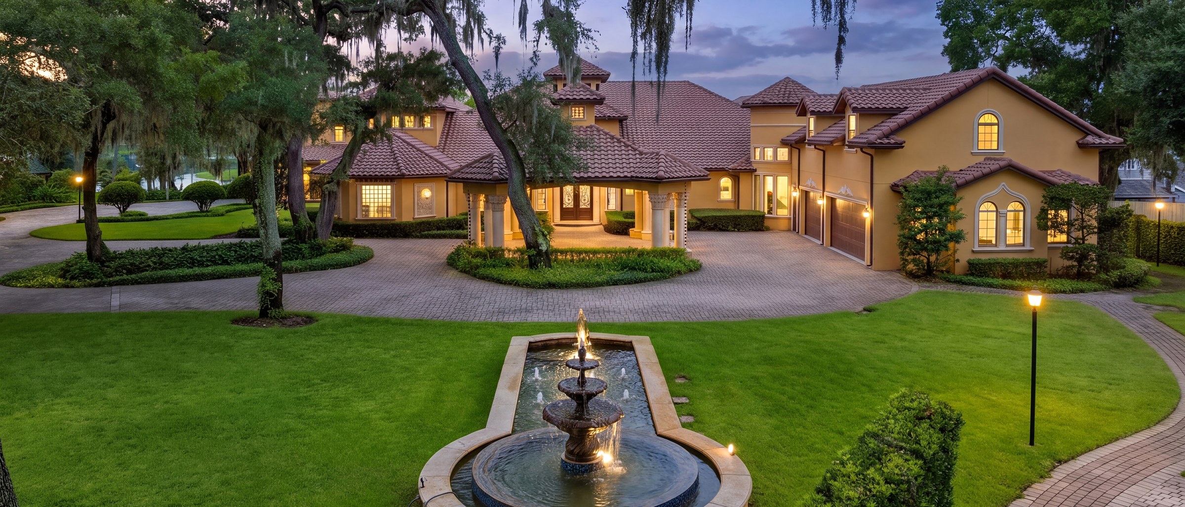 Twilight front elevation of the estate with fountain and circular drive